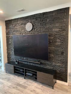 a flat screen tv mounted to the side of a stone wall in a living room