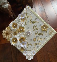 a white graduation cap with gold flowers and words for the plan i have for you