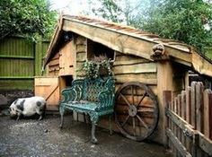 a pig is laying on the ground next to a bench and wooden structure with wheels