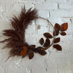 a wreath made out of dried leaves on a white brick wall