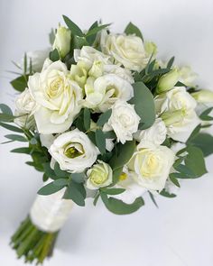 a bouquet of white roses and greenery on a white background with space for text