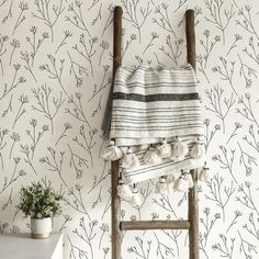 a chair sitting in front of a wall with flowers on it and a towel hanging from the back