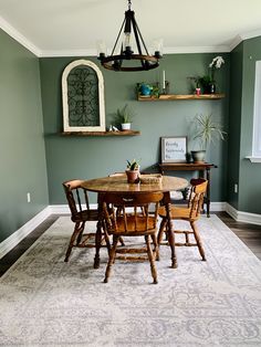 a dining room with green walls and white rug on the floor, wooden chairs around a round table