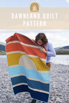 a woman holding up a quilt on the beach with text overlay that reads, dawnland quilt pattern