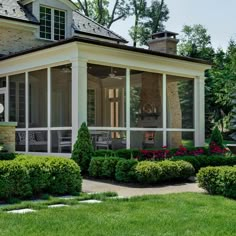 an image of a house with lots of windows and bushes in the front yard area