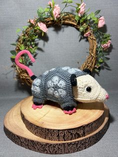 a small stuffed animal on top of a piece of wood with pink flowers in the background