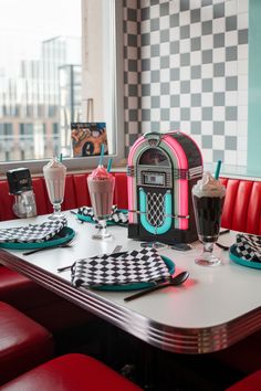 the table is set for two with red booths and checkered place mats on it