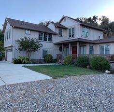 a large house with lots of windows on the front and side of it, surrounded by gravel