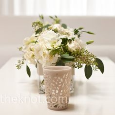 two vases with flowers in them sitting on a table next to each other,