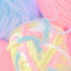 several balls of yarn sitting next to each other on top of a pink and blue surface