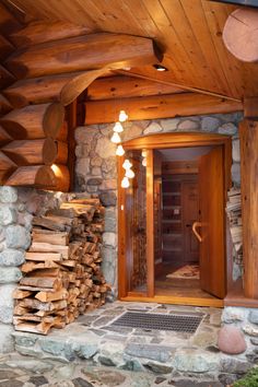 the entrance to a log cabin with wood stacked outside