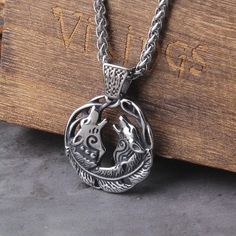 a silver necklace with an image of two horses in a circle on top of a wooden box