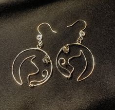 "Round silver earrings with a shape of a cats head profile inside it.  There's a tail and a clear crystal bead.   It's made with silver plate non tarnish nickel free wire.  Outer circle shape has been hammered for shine.  It's about 1-3/8\" round and a little over 2\" drop length.   Any different color crystal can be added too." Metal Jewelry With Cat Design, Metal Cat Design Round Jewelry, Elegant Silver Cat Design Earrings, Silver Round Crystal Earrings, Wire Wrapped, Silver Round Crystal Earrings Wire Wrapped, Hypoallergenic Silver Crystal Earrings, Teal Rings, Head Profile, Earring Hoops