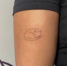 a woman's arm with a small tattoo of a sleeping cat on the side