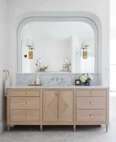 a bathroom vanity with two sinks and large mirror above it in a white walled room