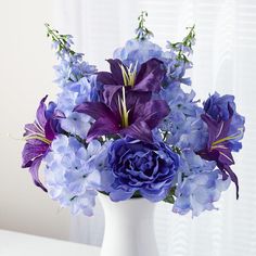 a white vase filled with purple and blue flowers