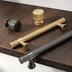 three different types of brass and black handles on a wooden table with two knobs