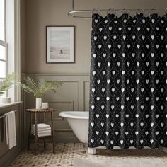 a black and white shower curtain with hearts on it in a bathroom next to a bathtub