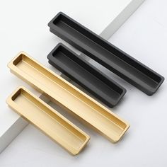 three black and gold drawer pulls sitting on top of a white table next to each other