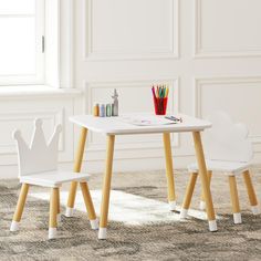 two children's table and chairs with pencils on them in front of a window