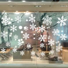 a store window with snowflakes on it's glass and shoes in the reflection