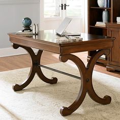 a desk with a laptop on it in front of a bookcase and bookshelf