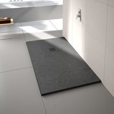 a bathroom with a black mat on the floor next to a bathtub and window