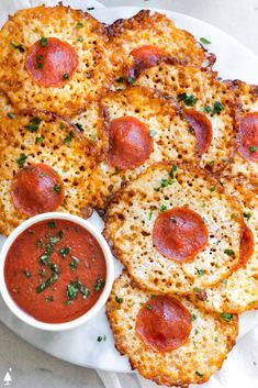 pizza with pepperoni and cheese on a white plate next to a small bowl of sauce