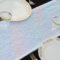 the table is set with white and gold plates, silverware, and napkins