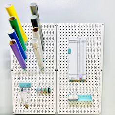 a pegboard with pens, markers and tubes attached to the pegs on it