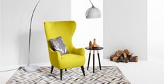 a yellow chair sitting on top of a rug next to a lamp