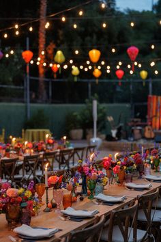 a long table with plates and flowers on it is set for an outdoor dinner party