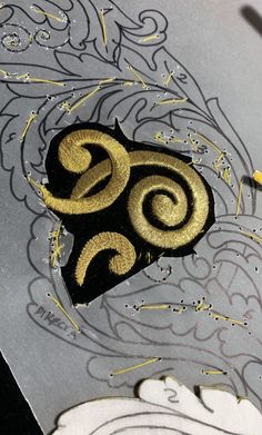 a close up of a piece of art with gold and black designs on it's surface