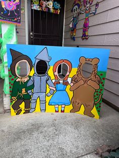 three cartoon characters are painted on a cardboard board in front of a house with other decorations