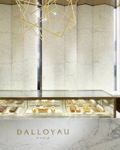 the interior of a pastry shop with marble counter tops and gold decorations hanging from the ceiling