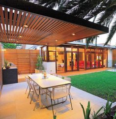 an outdoor dining area with table and chairs next to the swimming pool at night time