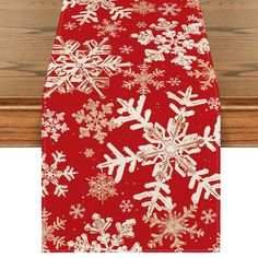 a red and white snowflaked table runner on a wooden surface with wood planks