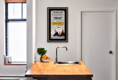 a kitchen with a sink, counter top and poster on the wall above it's faucet