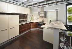 a kitchen with wooden floors and white cabinets, an island countertop and two green apples on the wall