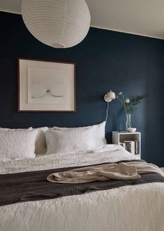 a bedroom with blue walls and white bedding