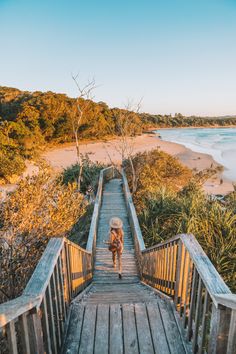 a person walking down a wooden walkway next to the ocean