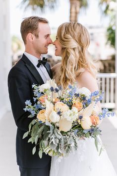 a bride and groom standing together in front of a palm tree