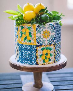 a decorated cake with lemons and limes on top sits on a wooden table