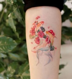 a woman's leg with flowers on it and a fish in the water behind her