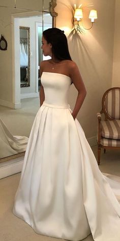 a woman standing in front of a mirror wearing a wedding dress