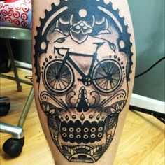 a man's leg with a bicycle skull tattoo on it