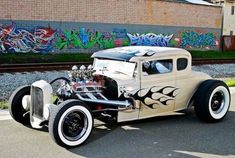 an antique car parked in front of a building with graffiti on the wall behind it