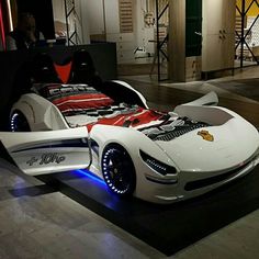 a white sports car with red and blue lights on it's bed in a showroom