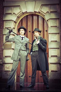 two men in suits and bowler hats are posing for the camera