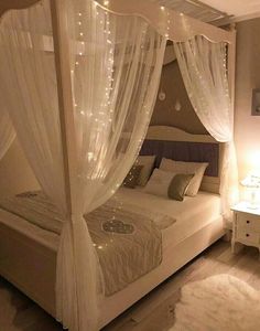 a bed with white curtains and lights on it